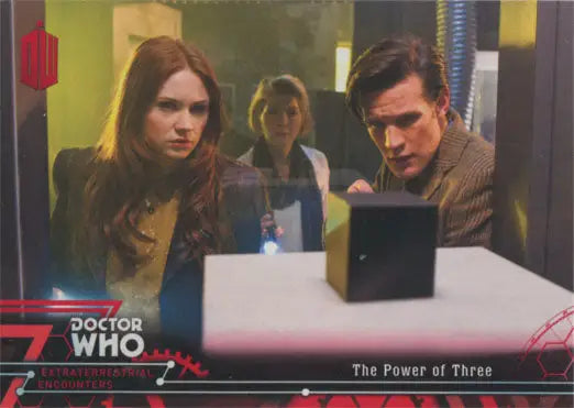 Three people discussing Doctor Who Red Parallel Chase Card around a black cube
