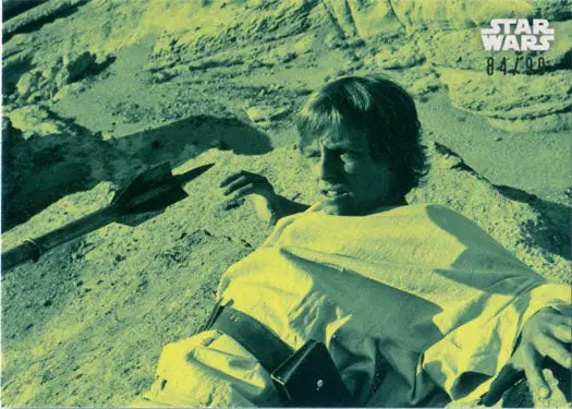 Young person in yellow outfit on sand, showcasing Star Wars trading cards design