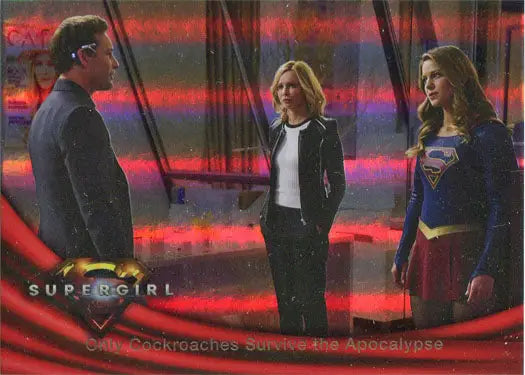 Three people with one in a Supergirl costume next to Supergirl Rainbow Foil Board Card