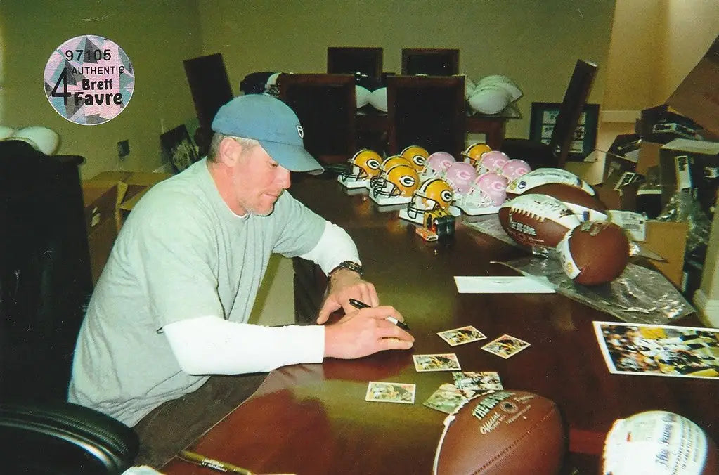 Man in light blue cap at table with 1991 Upper Deck Auto Brett Favre memorabilia