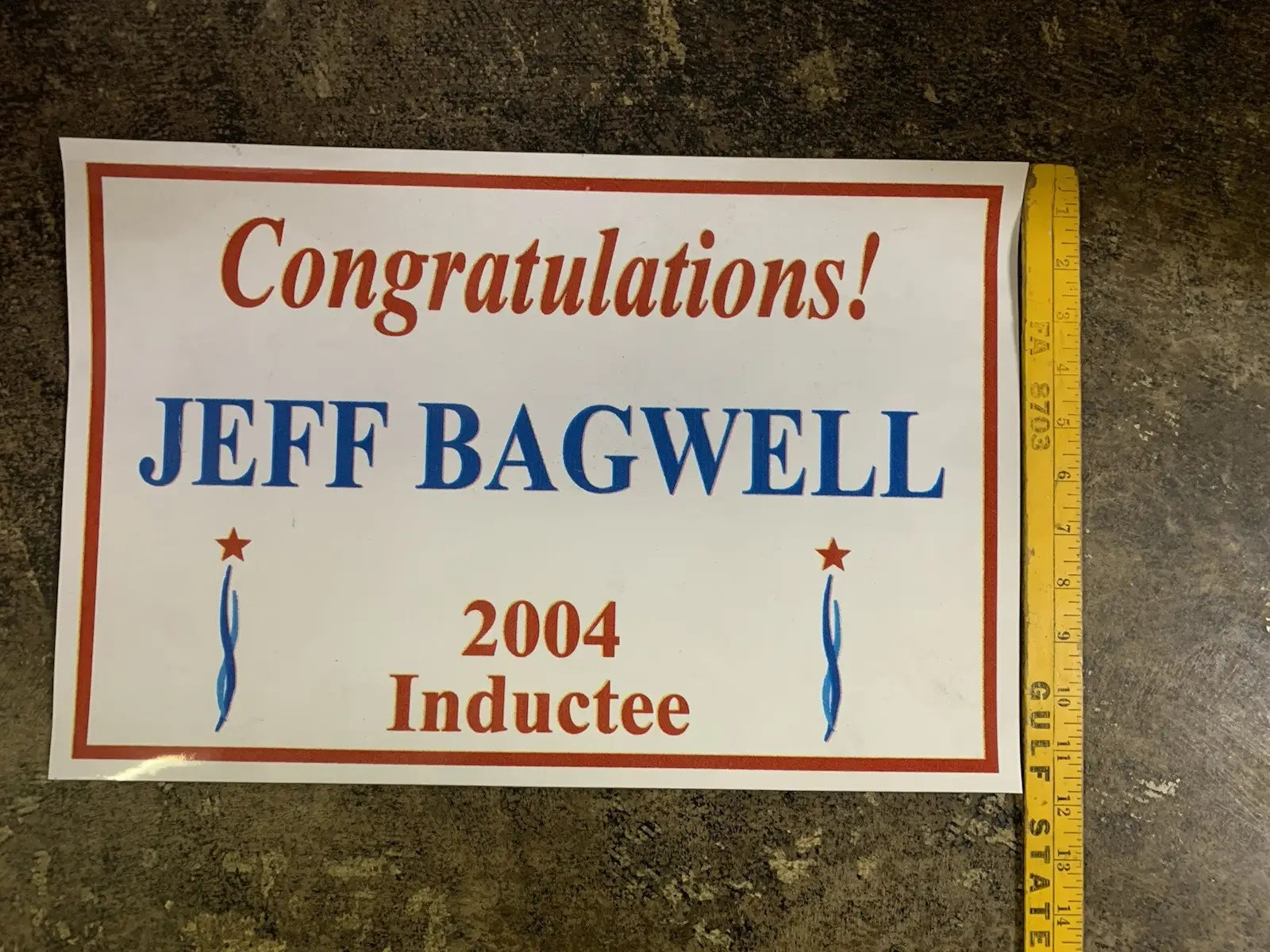 White rectangular sign with red lettering and blue accents featuring Jeff Bagwell Texas sports