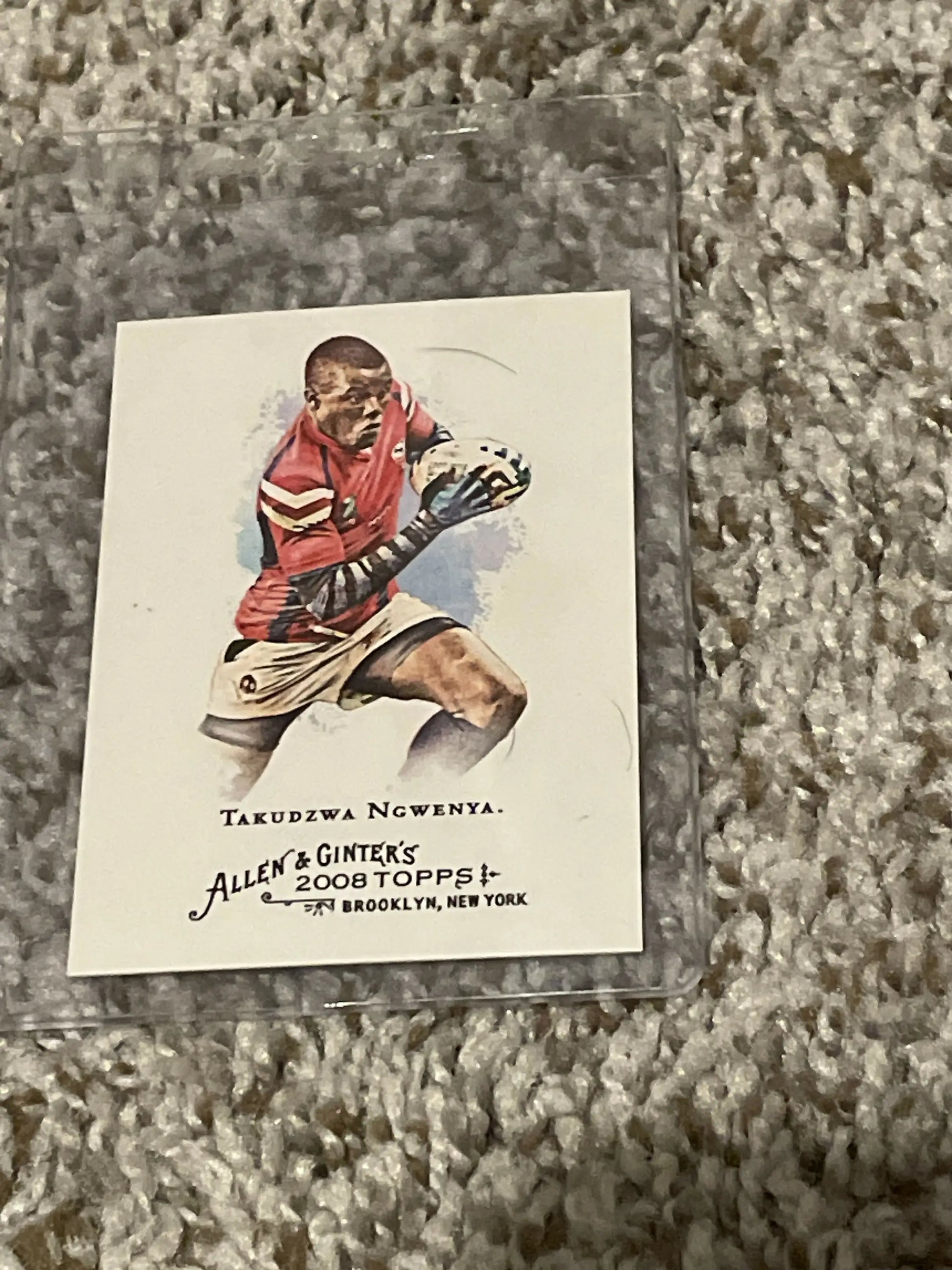 Baseball card of Takudzwa Ngwenya in red striped uniform catching a ball