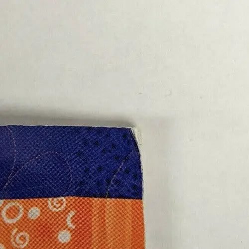 Quilt Challenge fabric corner with blue and orange patterns on store shelf pulls