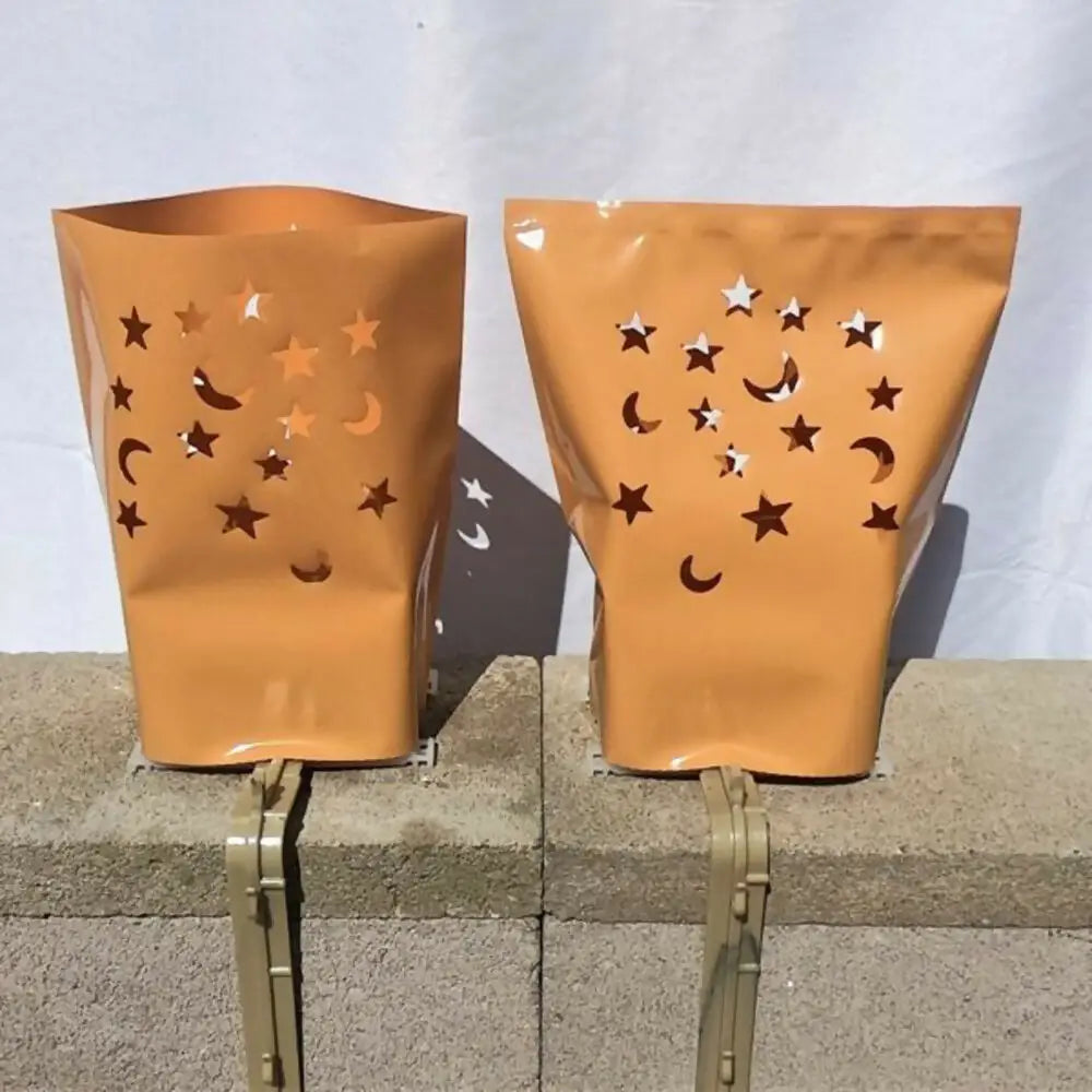 Two orange lantern-style luminarias bags with star and moon cutouts from Classic LUMINARY SET