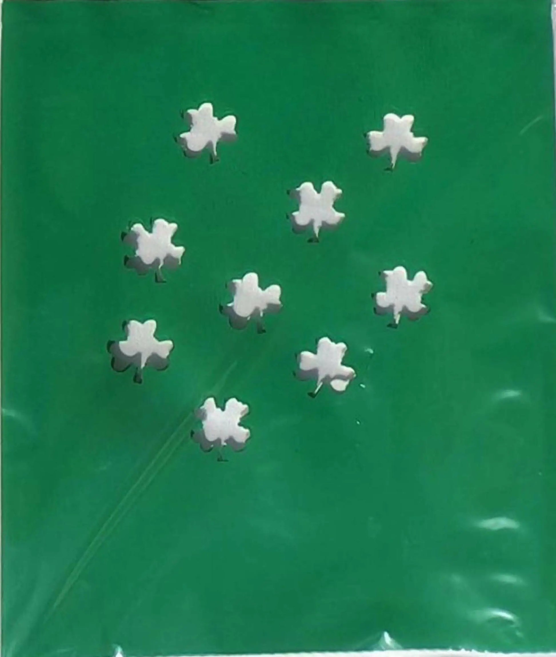 White shamrock-shaped candies from Classic LUMINARY SET on green background with luminarias bags