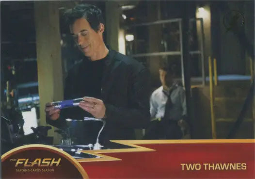 Man in dark shirt examines Flash Season 1 Gold Logo Parallel Chase Card #64 Two Thawnes