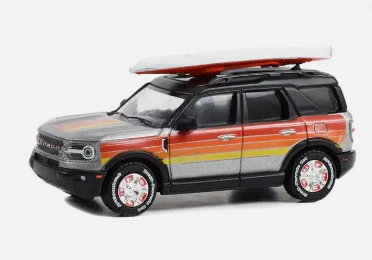 Land Rover Defender SUV with striped paint and surfboard atop Greenlight Bronco Sport Hobby Exclusive