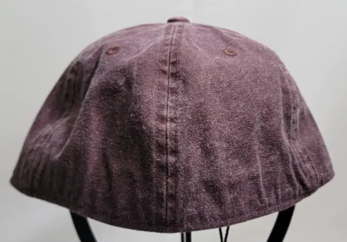Faded purple woven cotton cap with embroidered bar and textured worn appearance