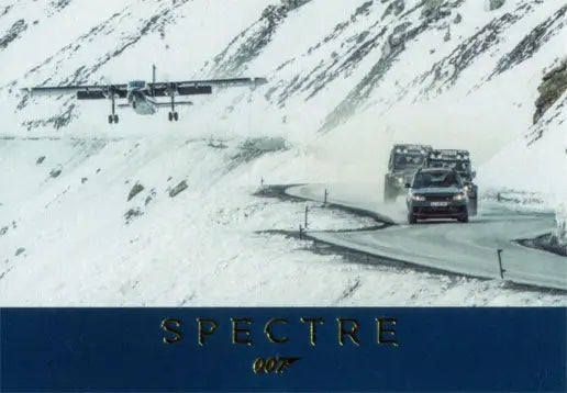 Airplane flying low over snowy mountain road showcasing Gold Foil Stamped SPECTRE card