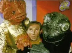 Person posing with costumed characters near Lost in Space Archives promo card