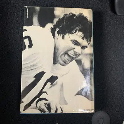 Signed Jim Plunkett story book cover featuring a football player and jersey