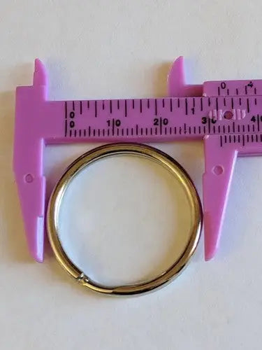 Gold-colored split key rings 27mm x 23mm being measured with pink caliper