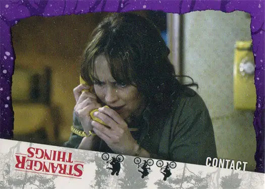 Woman with dark curly hair using a yellow telephone in a Stranger Things purple parallel trading card