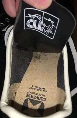 Worn black and white Dorsett Converse football cleats with footbed discoloration in box