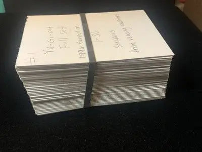 Stacks of Yu-Gi-Oh trading cards bound by a rubber band from Vintage 1996 Vending Sandy Lion set