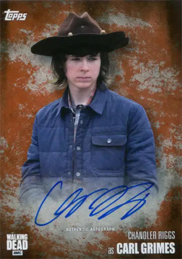 Trading card of Chandler Riggs as Carl Grimes in a black hat and blue jacket