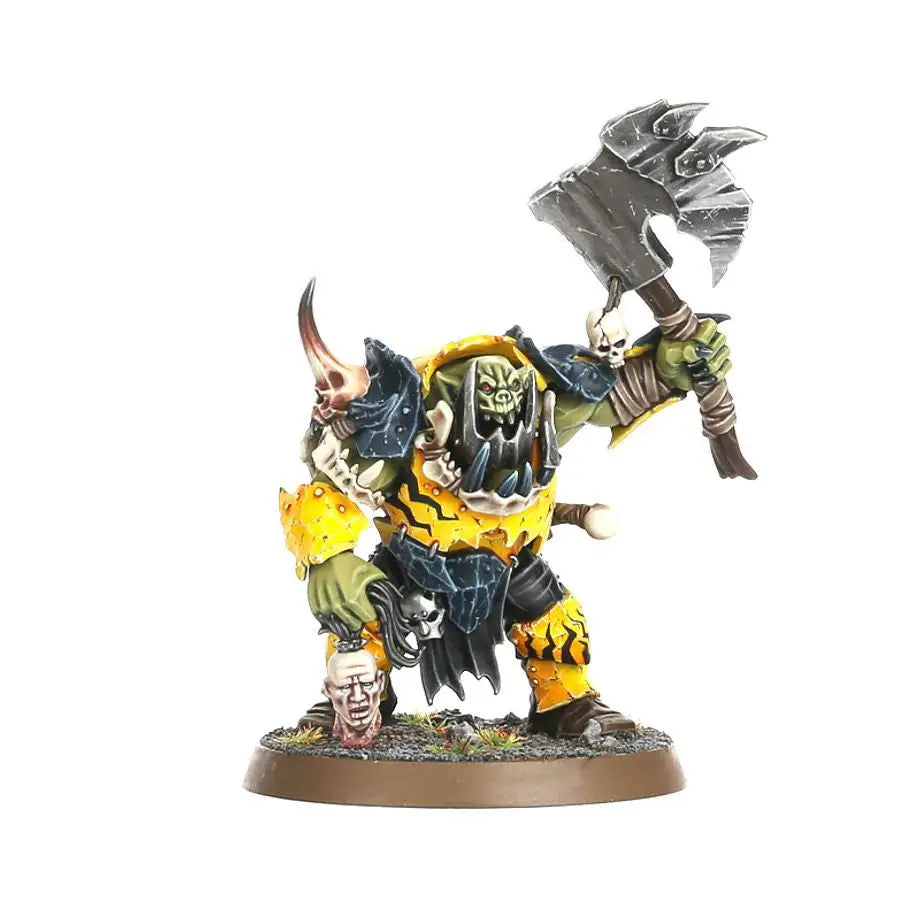 Green-skinned orruk brutes miniature with yellow and black armor wielding axe and severed head